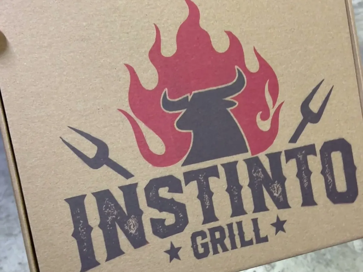 Caja de envío kraft impresa a color con el logo de un restaurante en la tapa