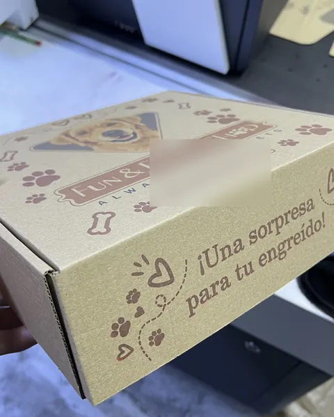 Caja de envío kraft de una tienda de mascotas con el retrato de un perro y la frase «Una sorpresa para tu engreído»