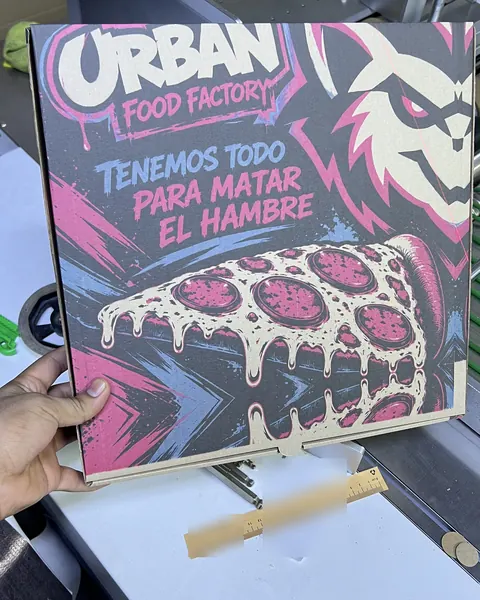 Caja de pizza con fondo impreso a todo color, con una porción de pizza ilustrada y la frase «Tenemos todo para matar el hambre»